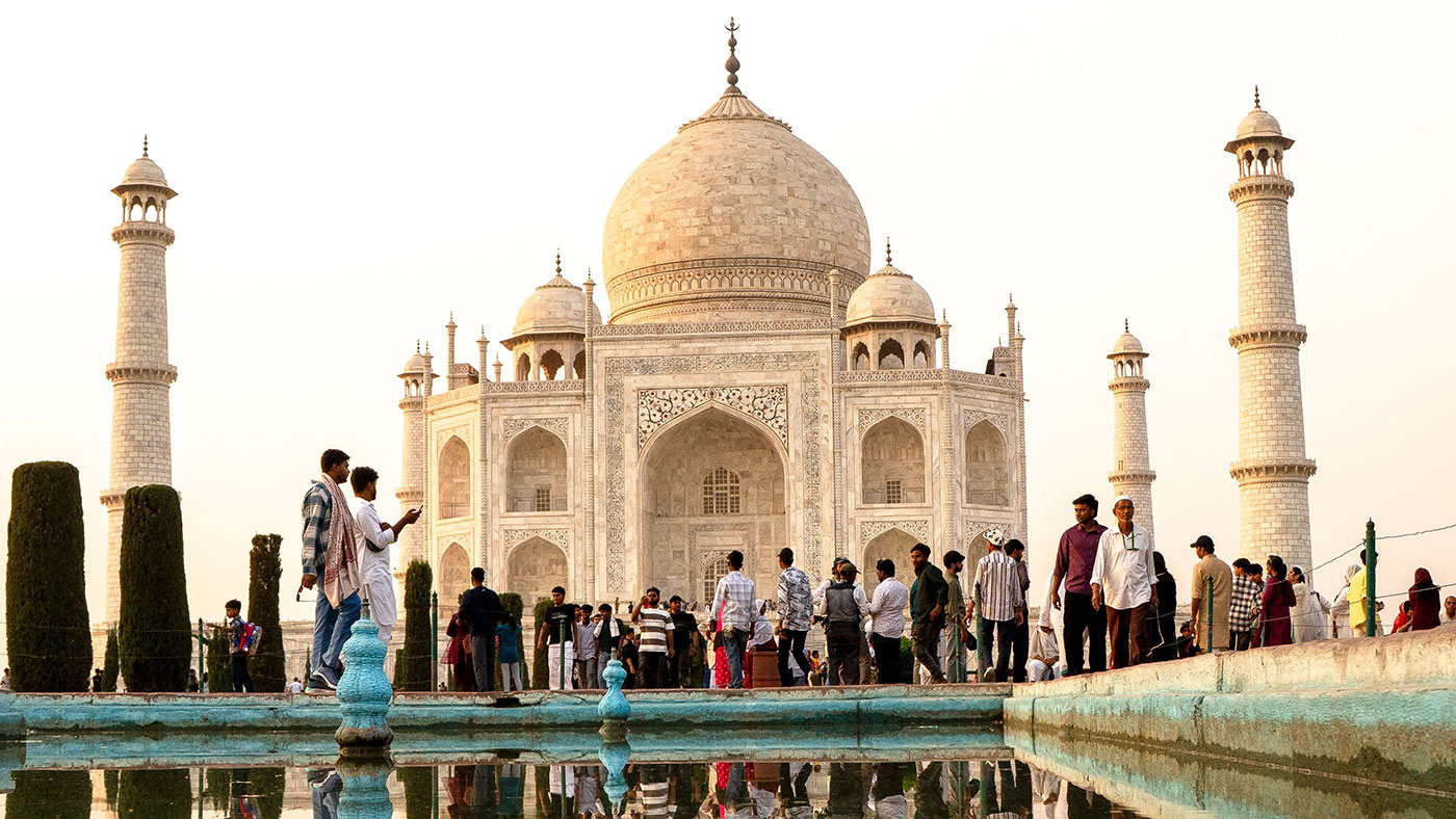 Touristen vor dem Taj Mahal in Agra, gespiegelt im Wasserbecken